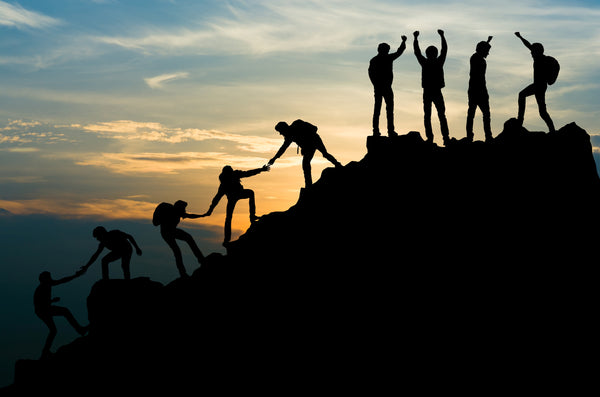 group of people reaching a mountain peak